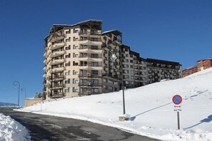 Ein mehrstöckiges Gebäude mit Balkonen, einem Verbotsschild und einem schneebedeckten Hang.