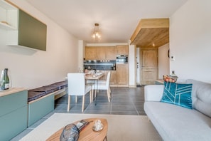 Un espacio habitable compacto con comedor, kitchenette y sofá decorado con cojines.
