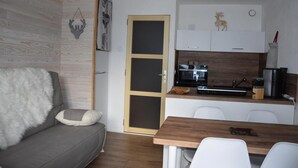 A compact living space with a grey sofa, a wooden dining table, a kitchenette with a microwave, and a small cabinet. - 1st floor, balcony, tv, ski locker, 21m², Pralognan-la-Vanoise (Pralognan-la-Vanoise)