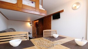 A dining area with a wooden table, four chairs, and a TV mounted on the wall. - 100m from ski slopes, 6th floor, balcony, tv, 25m², Les Arcs (Les Arcs)