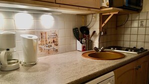 Ett kök med en diskho, en kaffebryggare och en mikrovågsugn.