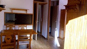 A wooden dining table with chairs, a television, and a wooden cabinet. - 50m from ski slopes, 4th floor, view mountain, balcony, tv, 27m², Méribel-Mottaret (Méribel - Les Allues)