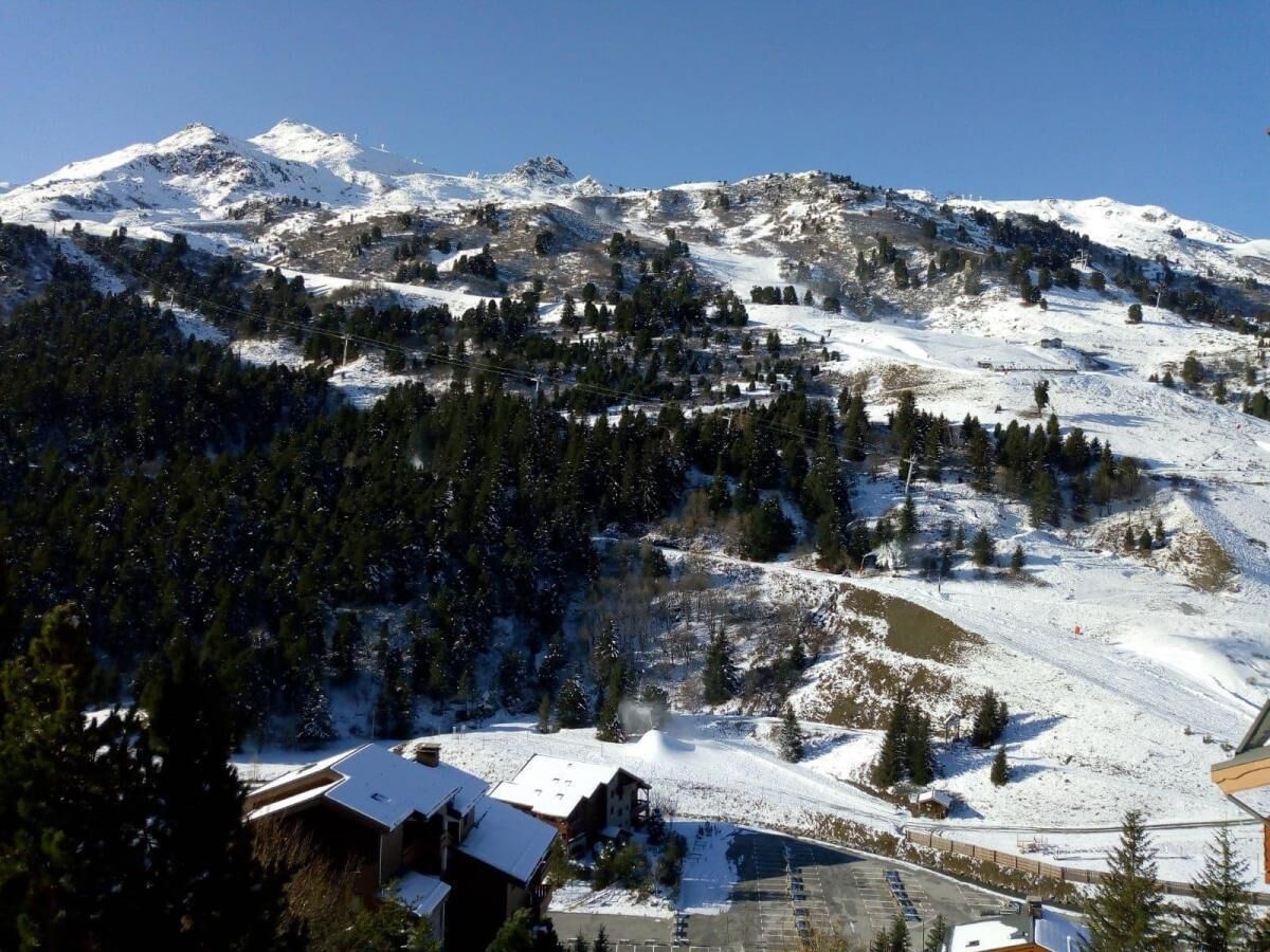 A mountainous landscape with snow-covered slopes and a small building with a snow-covered roof.
