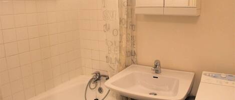 A bathroom with a bathtub, a sink, and a cabinet.