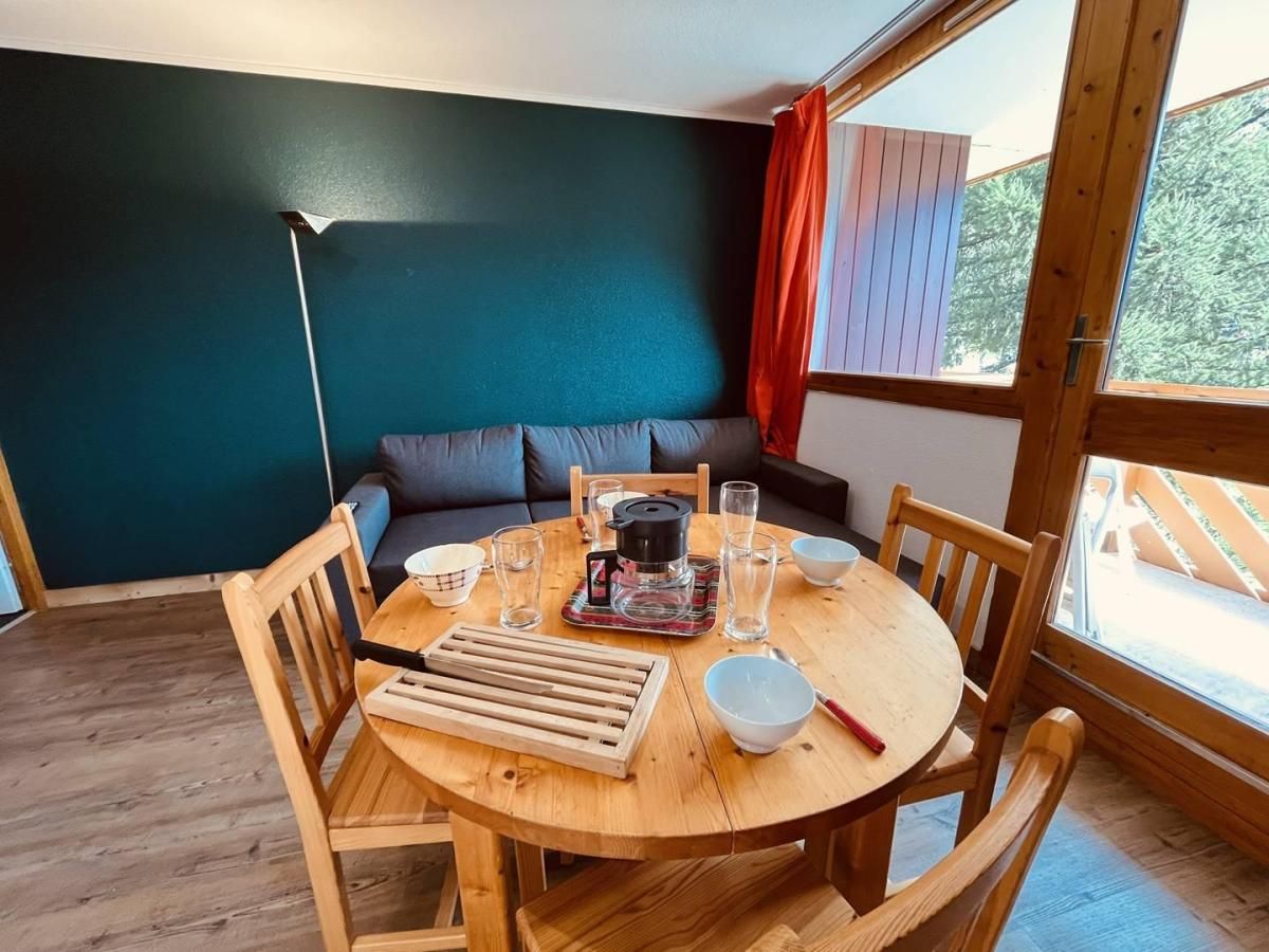 A cozy dining area with a round wooden table, chairs, and a coffee maker.
