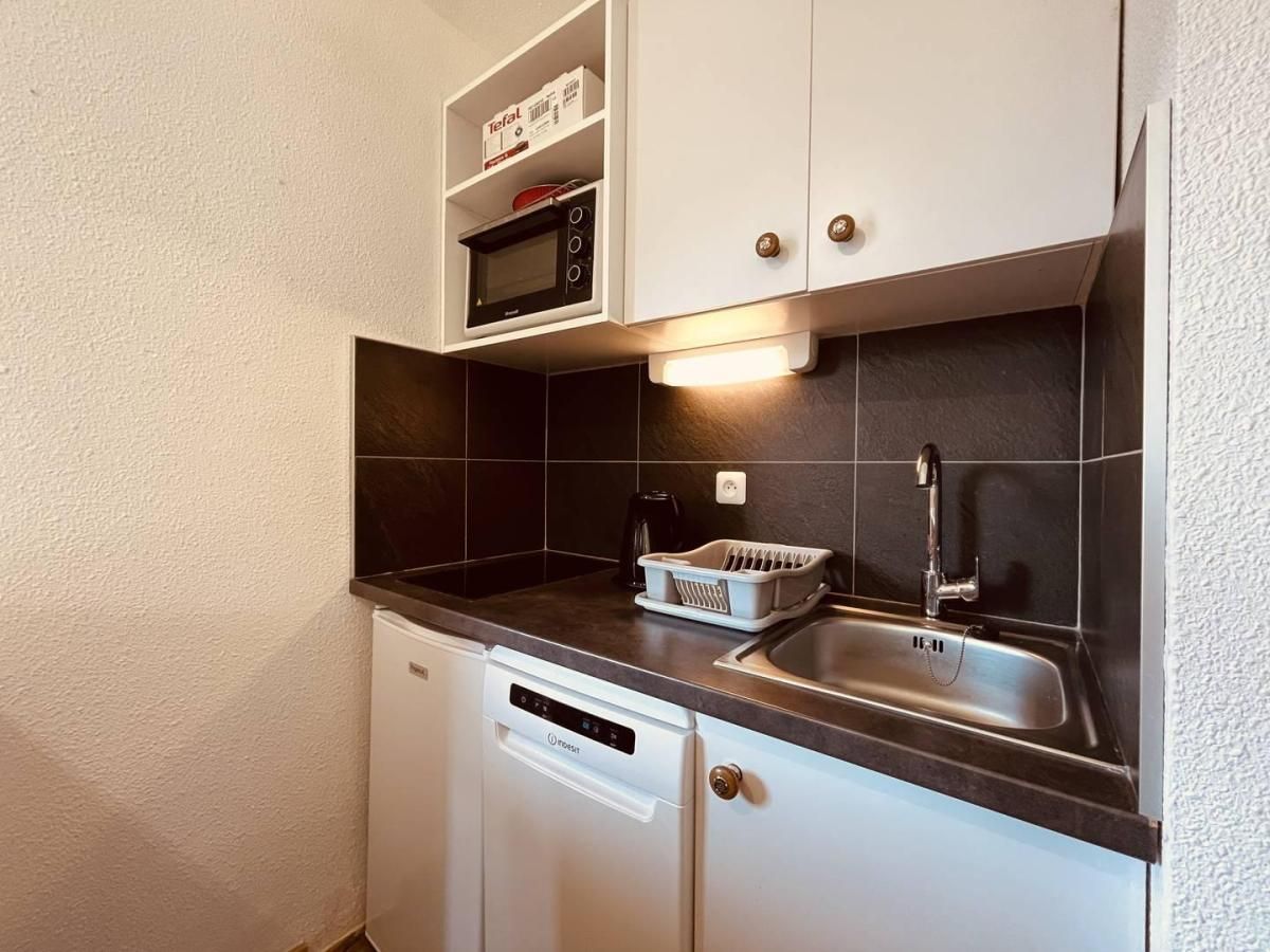 A compact kitchen with a dishwasher, a microwave, a sink, and a coffee maker.