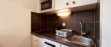 A compact kitchen with a dishwasher, a microwave, a sink, and a coffee maker.