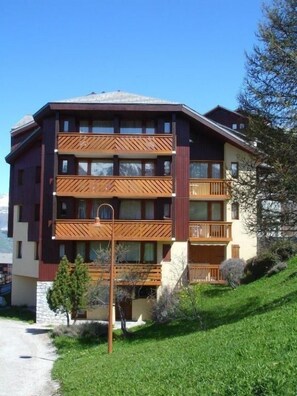 A multi-story hotel with balconies, a clear sky, and a grassy slope. - 180m from ski slopes, 3rd floor, balcony, tv, ski locker, 34m², Peisey-Vallandry (Landry)