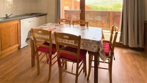 Une cuisine avec des meubles de rangement en bois, un four à micro-ondes et une table à manger avec des chaises.