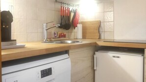 Une cuisine compacte dotée de meubles en bois, d’un four à micro-ondes, d’un lave-vaisselle et d’un réfrigérateur.