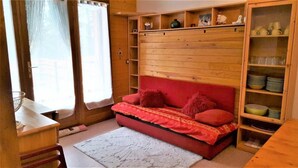 Une pièce chaleureuse avec un lit en bois, un petit bureau et une étagère remplie de vaisselle.