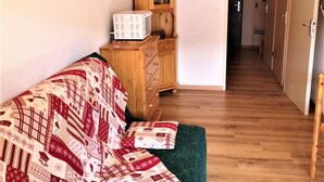 A cozy room with a green sofa, wooden cabinet, and a microwave on top.