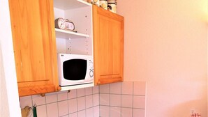 A compact kitchen with wooden cabinets, a microwave, a stove, and a dishwasher.