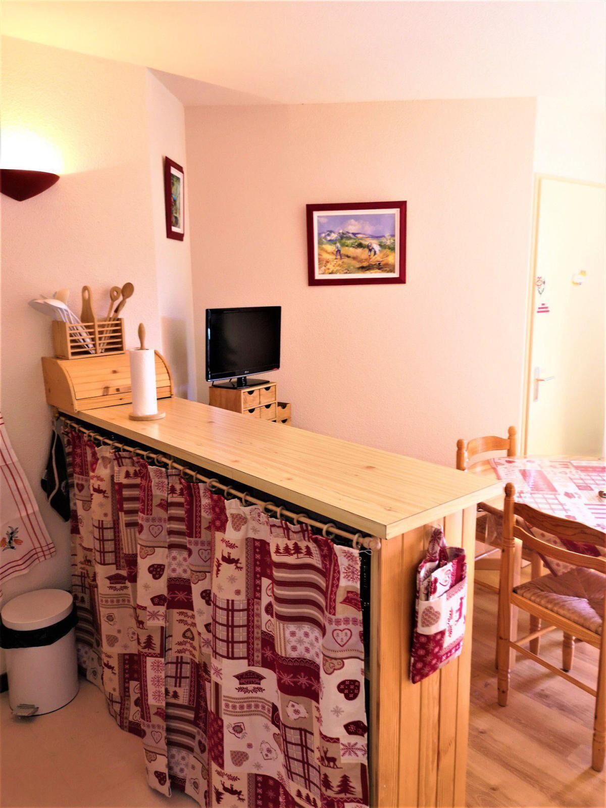 Eine kleine Küchenzeile mit Holztisch, Fernseher und Esstisch mit Stühlen.