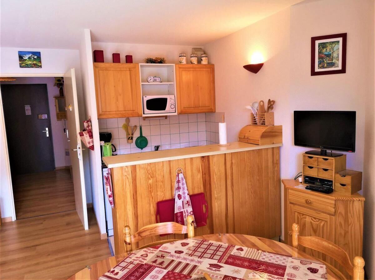 Una cucina compatta con mobili in legno, un forno a microonde e una zona pranzo con tavolo e sedie.