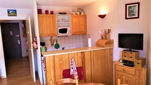 A compact kitchen with wooden cabinets, a microwave, and a dining area with a table and chairs.