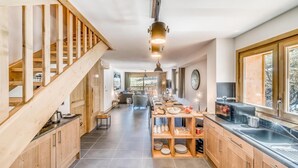 A modern kitchen with wooden cabinetry, a central island, and a staircase leading to an upper level.