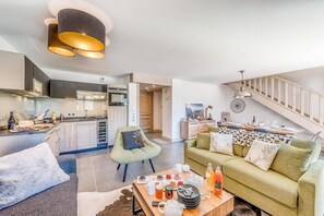 A modern kitchen with a dining area, a sofa, and a coffee table with breakfast items.