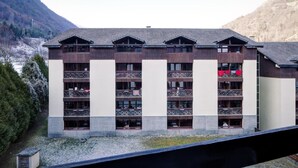 A multi-story hotel with balconies, set against a mountainous backdrop.