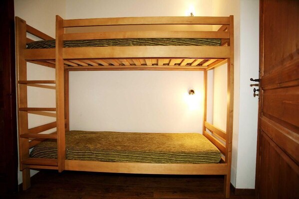 A bunk bed with a wooden frame and a single light fixture above the middle bunk.