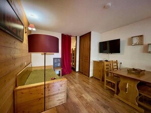 A room with a bed, a desk, a TV, and a wooden cabinet.