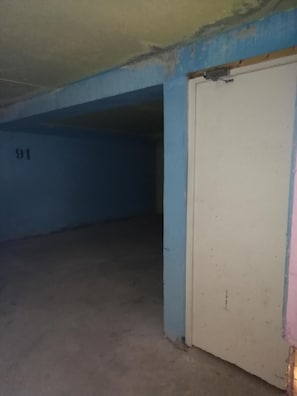 A room with a blue wall, a white door, and a concrete floor.