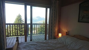 A bedroom with a bed, a nightstand, a lamp, and a view of a balcony with a railing. - Ski-in/ski-out & foot of the slopes, 1st floor, view ski slopes, balcony, tv, ski locker, 65m² (Les Arcs)