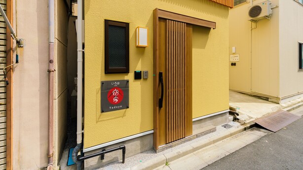 Un edificio con fachada amarilla, una puerta de madera y un letrero con caracteres japoneses.