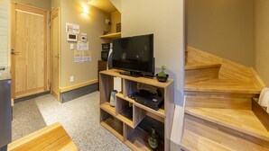 Una sala de estar moderna con televisor de pantalla plana, mobiliario de madera y una escalera.