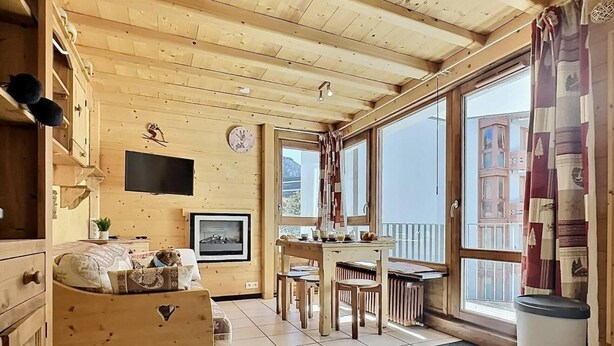 Une charmante cabane en bois avec un coin repas, un canapé et un téléviseur.