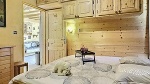 Une pièce aux murs lambrissés, avec un lit, une petite table et une chaise.