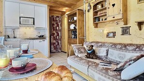 Un salon chaleureux avec un canapé, un ours en peluche et un coin repas où la table est mise pour le petit-déjeuner.