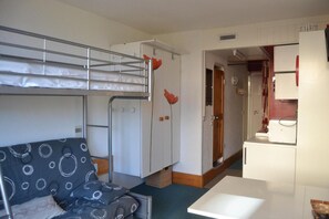 Ein kleines Zimmer mit Etagenbetten, einer Küchenzeile und einer gemütlichen Sitzecke.