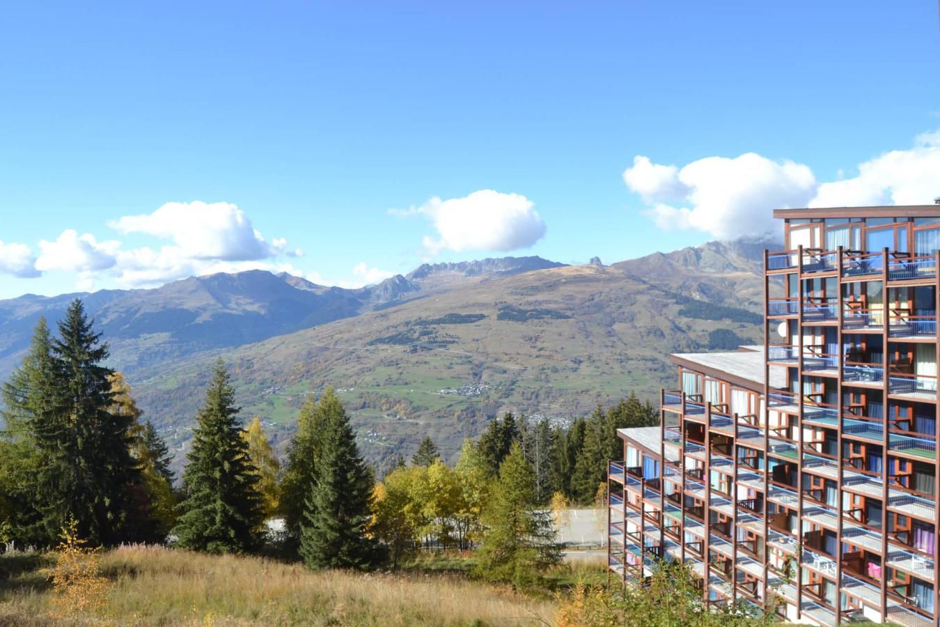 Ein modernes Gebäude mit mehreren Balkonen mit Blick auf eine gebirgige Landschaft.