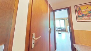 A hallway with a wooden door leading to a room with a bed and a painting on the wall. - 1st floor, balcony, tv, 26m², Le Grand Bornand (Le Grand-Bornand)