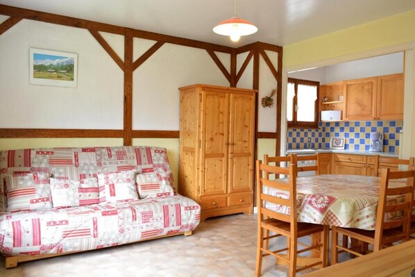 Una sala de estar acogedora con un sofá estampado, un mueble de madera y un comedor con mesa y sillas.