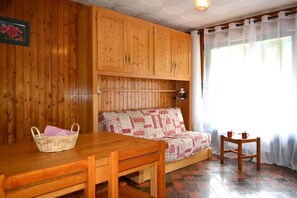 Een houten kamer met een bank, een tafel en een bijzettafeltje met kopjes.