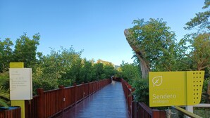 Un puente de madera con un cartel que indica servicios como casa club, casa junto al lago y piscina.