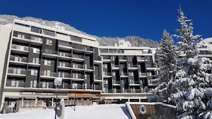 Ein mehrstöckiges Hotel mit Balkonen, einem Skiverleih und einem Restaurant.