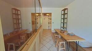 Ein moderner, gut beleuchteter Raum mit einem Holzespeisetisch, Stühlen und einer Glastrennwand.
