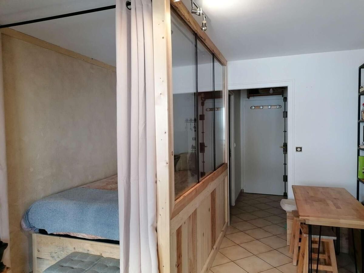 A small, compact room with a bunk bed, a wooden table, and a sliding glass door leading to another room.