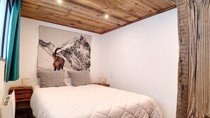 A bedroom with a large bed, wooden ceiling, and a mountain painting on the wall. - 200m from ski slopes, Ground floor, terrace, tv, 42m², Les Menuires (Les Menuires)