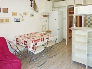 Una cocina compacta con una mesa de comedor preparada para dos personas, un refrigerador y un microondas.