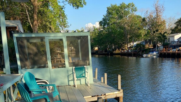 Un muelle con un área de descanso cubierta y un pequeño edificio con puerta mosquitera.