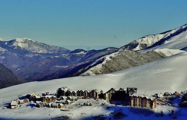 A snow-covered mountain village with traditional chalet-style buildings, a ski slope, and a clear blue sky. - 100m from resort center, 1st floor, view ski slopes, jacuzzi, hammam, balcony, tv, ski locker, 52m² (Germ)