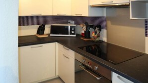 Eine kleine Küche mit einer Mikrowelle, einem Backofen und einem Messerset auf der Arbeitsfläche.