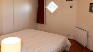 Ein Schlafzimmer mit Bett, Fenster, Heizkörper und Lampe.