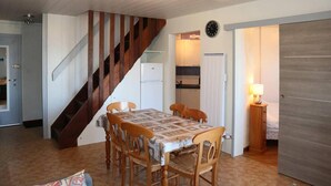 Ein Essbereich mit Holztisch und -stühlen, eine Treppe, ein Küchenbereich und eine Tür zu einem anderen Raum.
