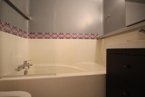Bathroom features a bathtub, toilet, and storage cabinet.