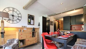 Een eetruimte met een houten tafel, rode stoelen en een klok aan de muur.